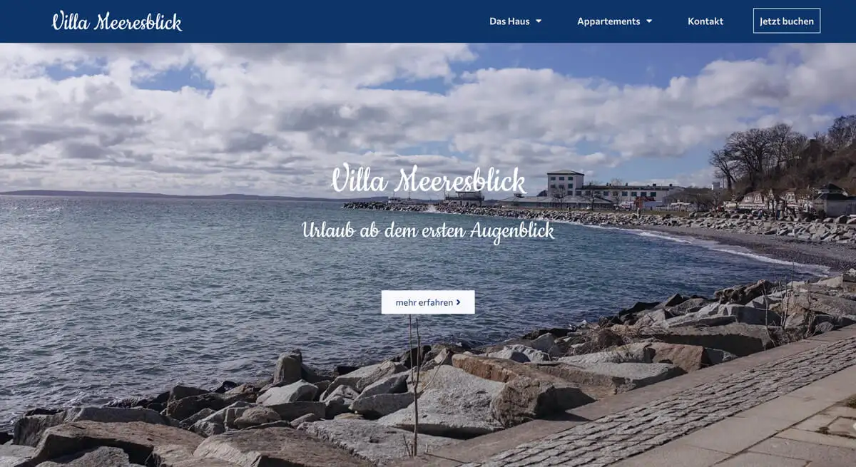 Website der Villa Meeresblick mit Küstenpanorama, steinigem Strand und bewölktem Himmel.