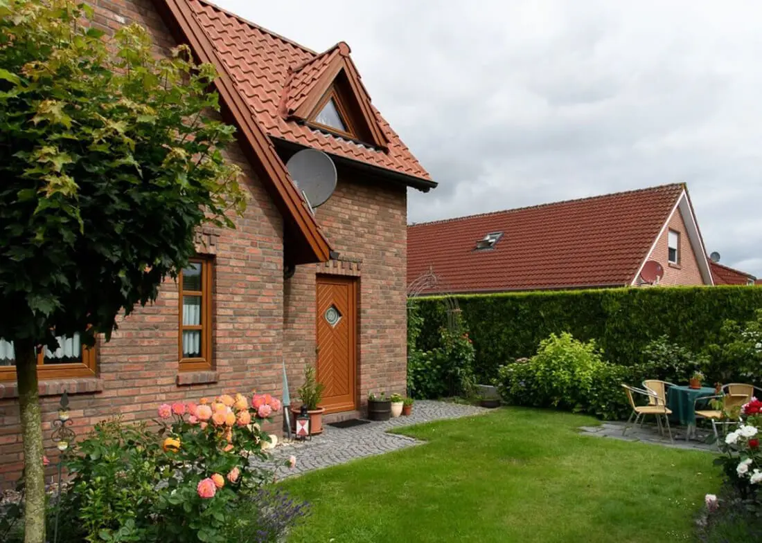 Ferienhaus Henny mit Backsteinfassade, Garten, Terrasse und rotem Ziegeldach.