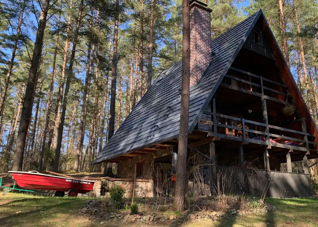 Ferienhaus Marianna steht zwischen hohen Kiefern mit Balkon und Kamin.
