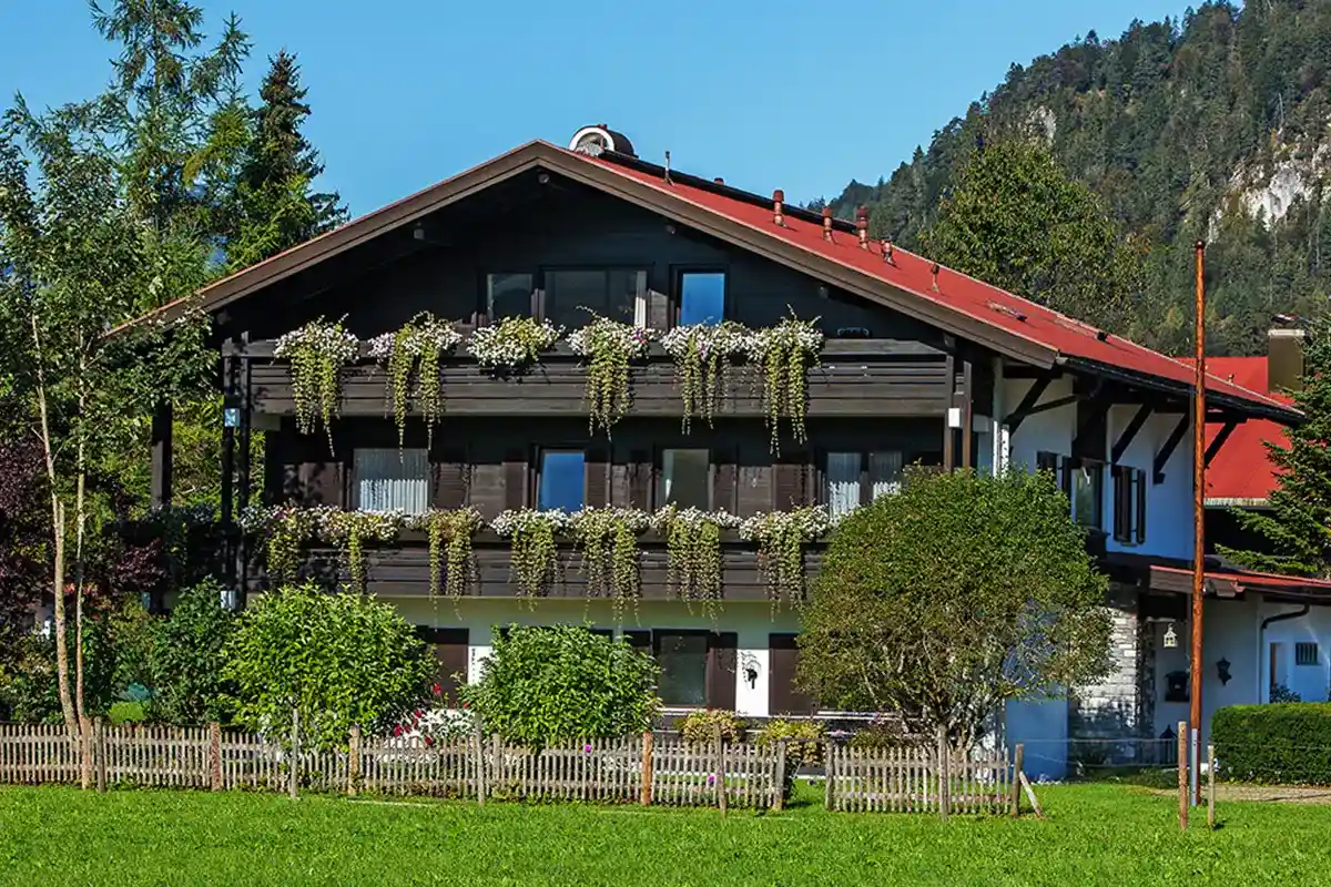 Gästehaus Wiesegg mit Balkonen und Blumenschmuck steht vor einer Berglandschaft.