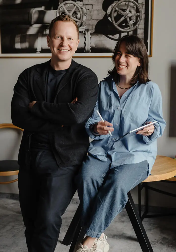 Jacek und Agnes stehen gemeinsam vor einer dunklen Wand.