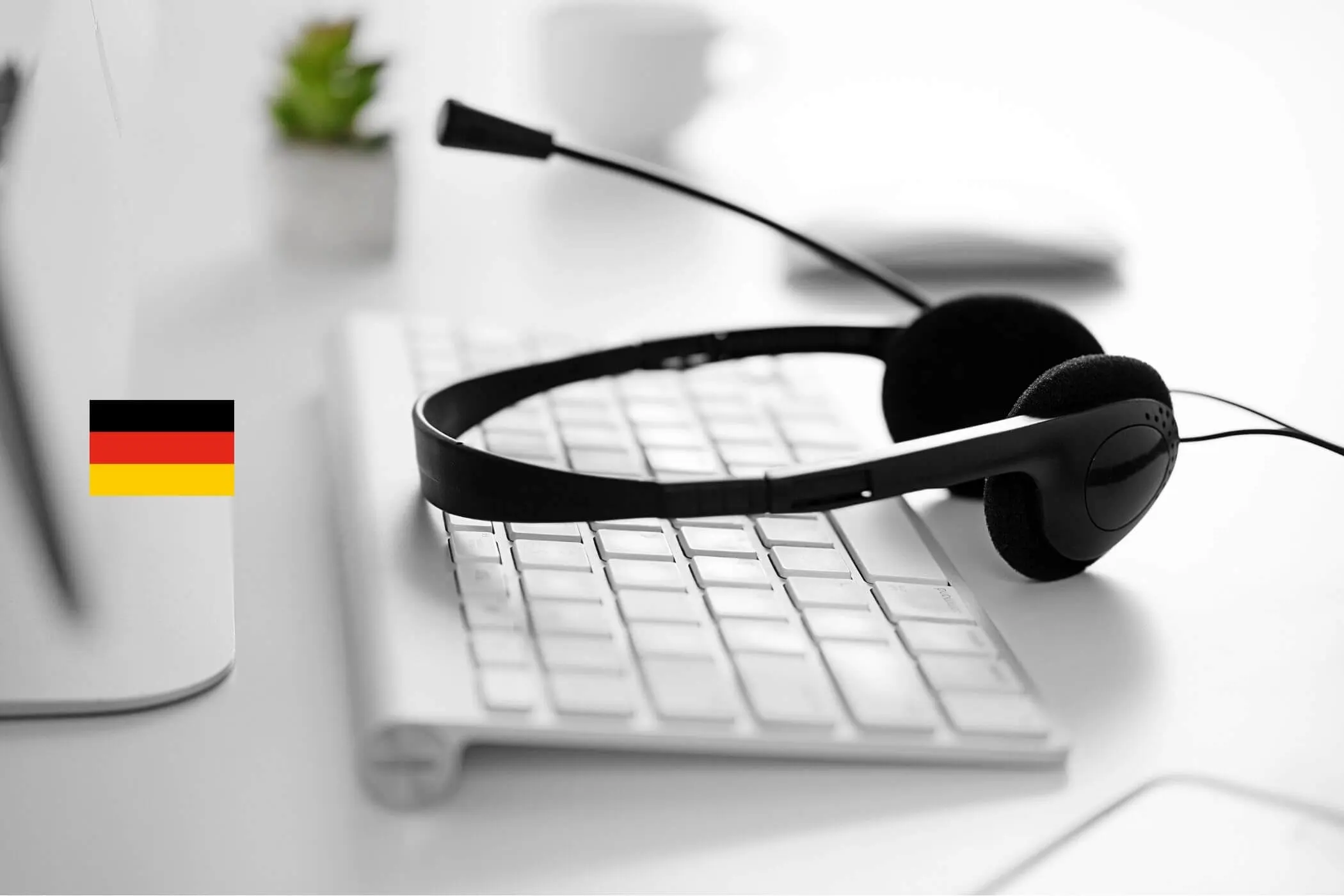 Schwarzes Headset liegt auf einer Tastatur neben einer Deutschlandflagge.