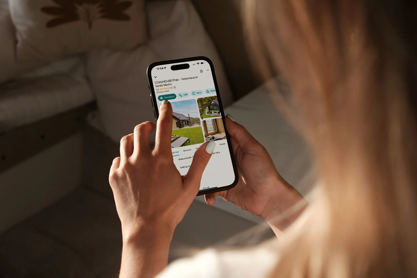 Frau betrachtet eine Ferienhaus-Seite auf Google Maps mit ihrem Smartphone.