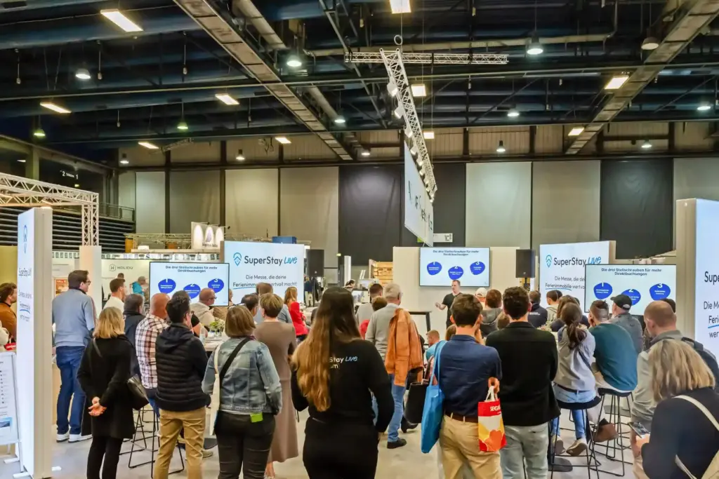 Zahlreiche Besucher verfolgen einen Vortrag auf einer Messe für Ferienvermietung.