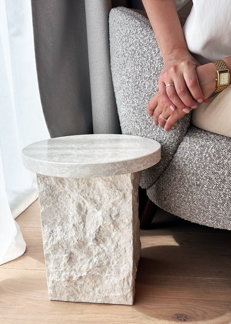 Modernes Interior-Detail mit Naturstein-Beistelltisch und grauem Designersessel in stilvoller Ferienunterkunft