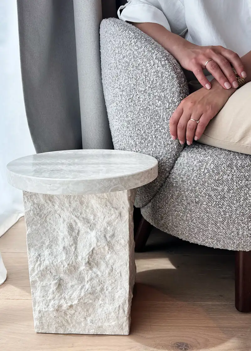 Grauer Sessel und heller Beistelltisch prägen eine ruhige moderne Zimmerecke.