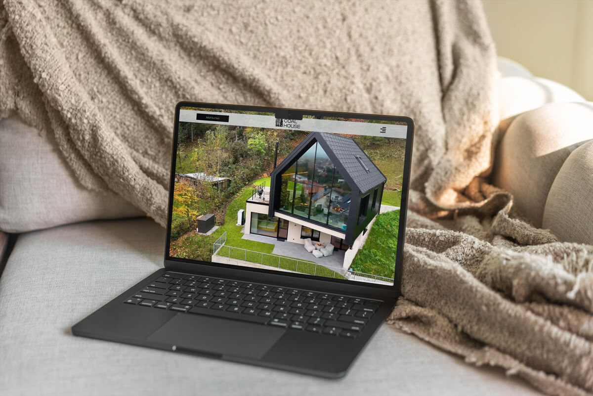 Moderne Ferienhaus-Website mit Drohnenaufnahme auf Laptop im gemütlichen Ambiente