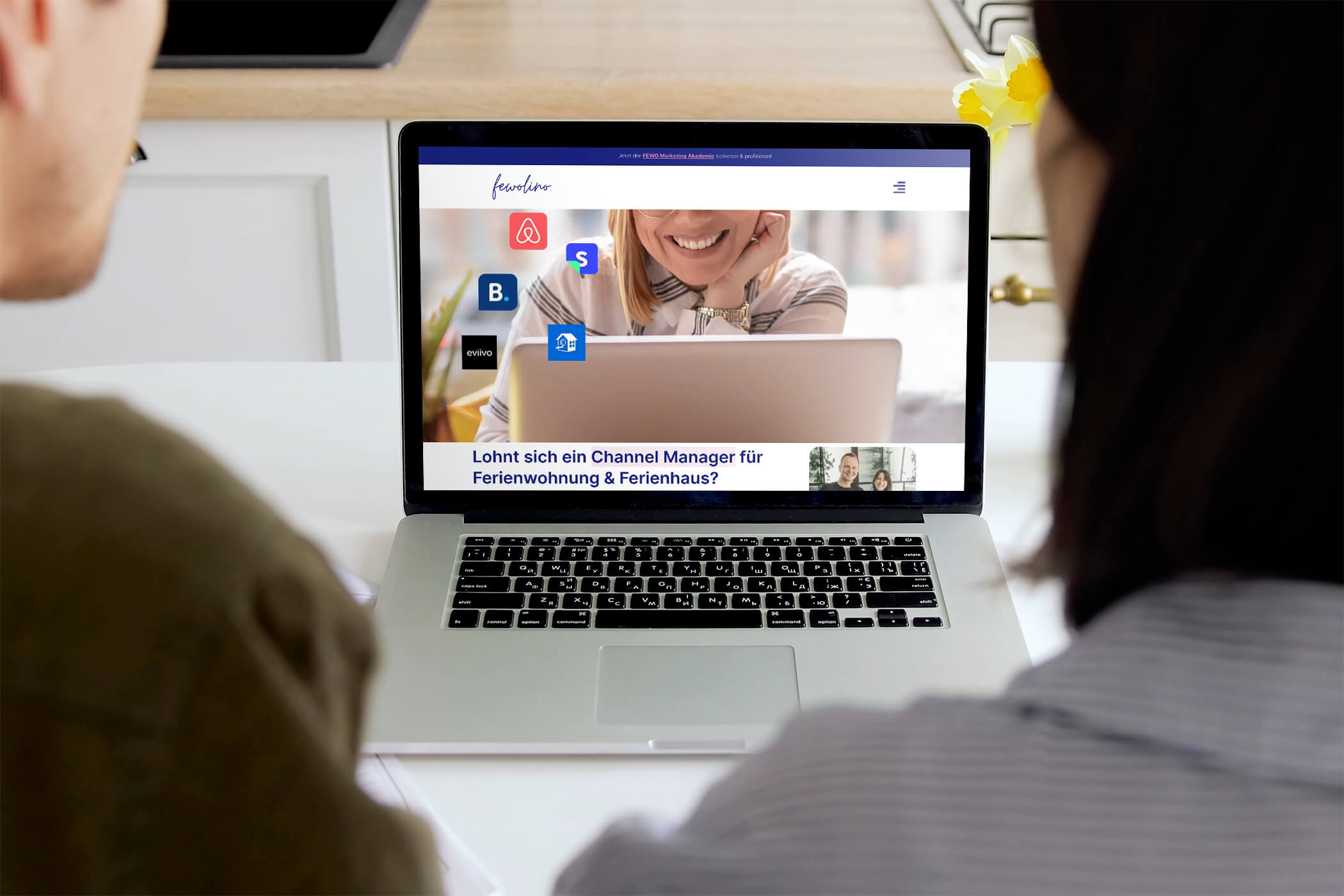 Laptop mit Fewolino Tutorial über Channel Manager für Ferienwohnung und Ferienhaus, zwei Gastgeber schauen zu