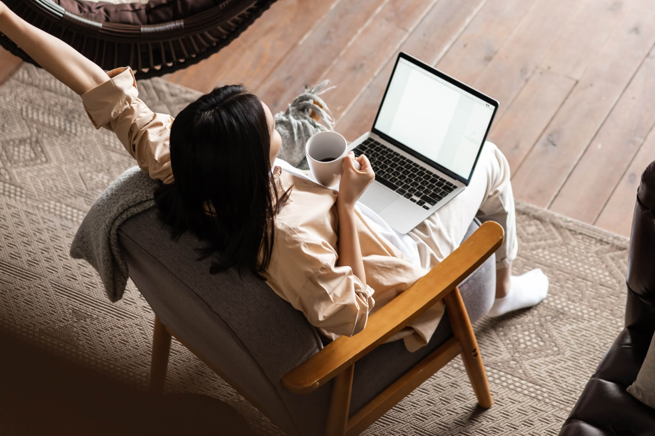 Frau mit Laptop und Kaffee bei entspannter Ferienwohnungsplanung