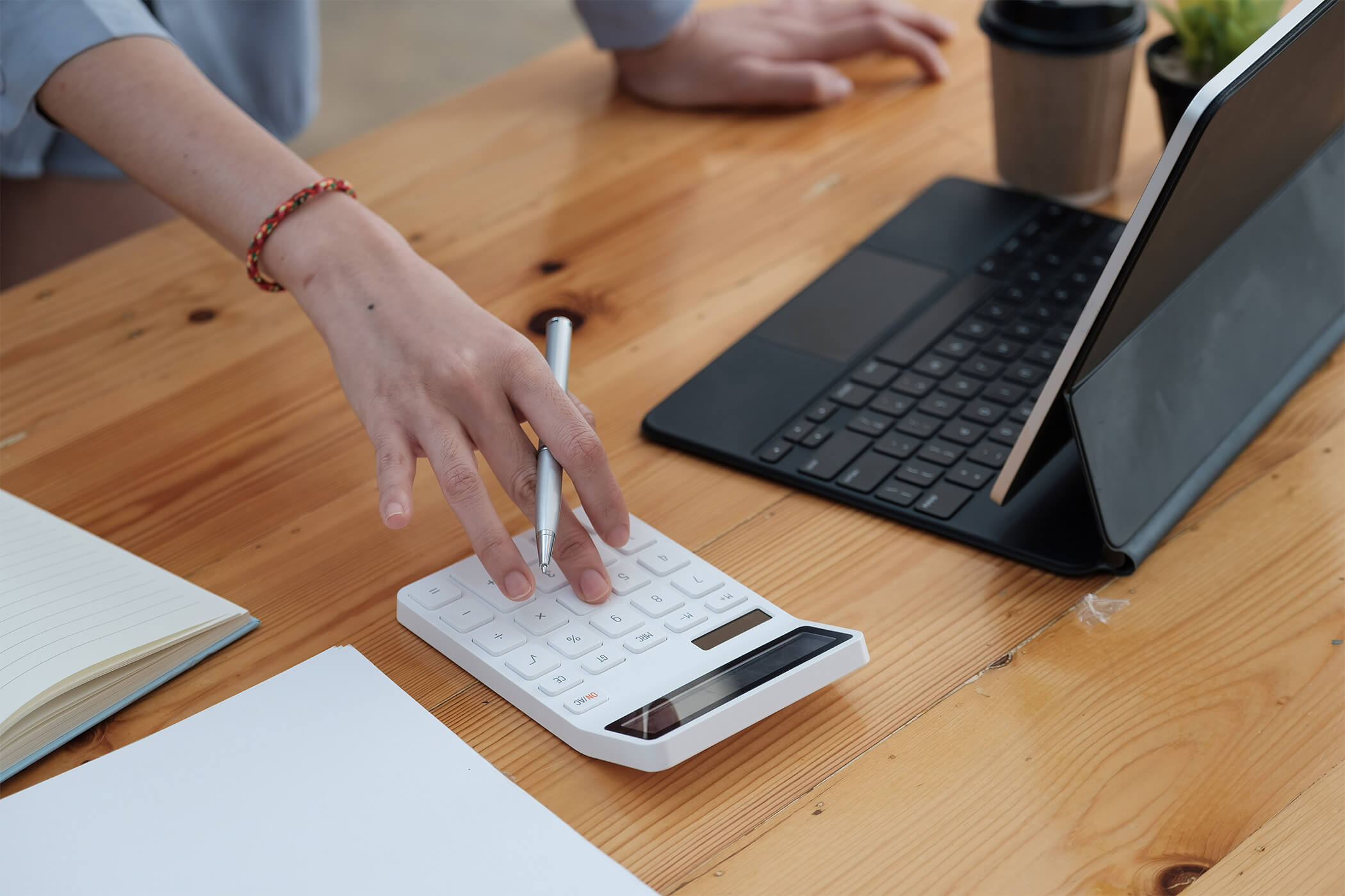 Person berechnet Booking.com Provision und Rabatte mit Rechner und Laptop