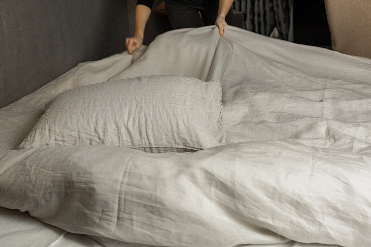 Leinenbettwäsche wird auf einem Bett in einer Ferienwohnung gerichtet