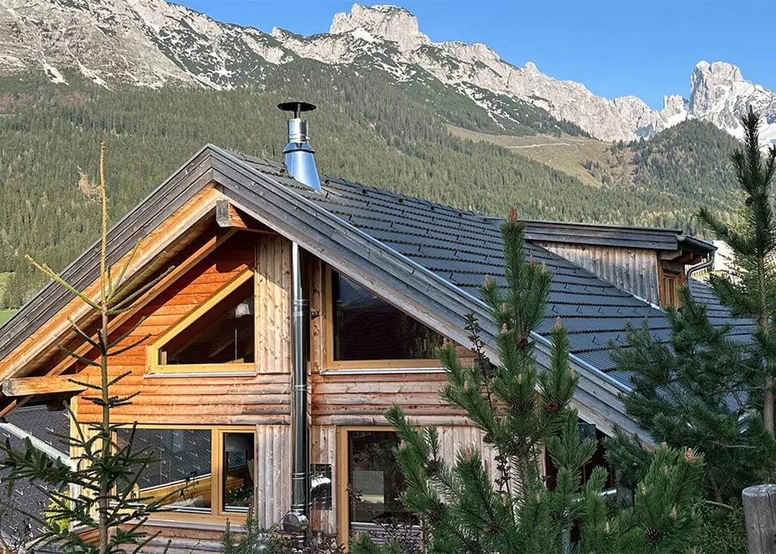 Chalet Bischofsmütze aus Holz vor beeindruckender Bergkulisse in der Alpenregion.